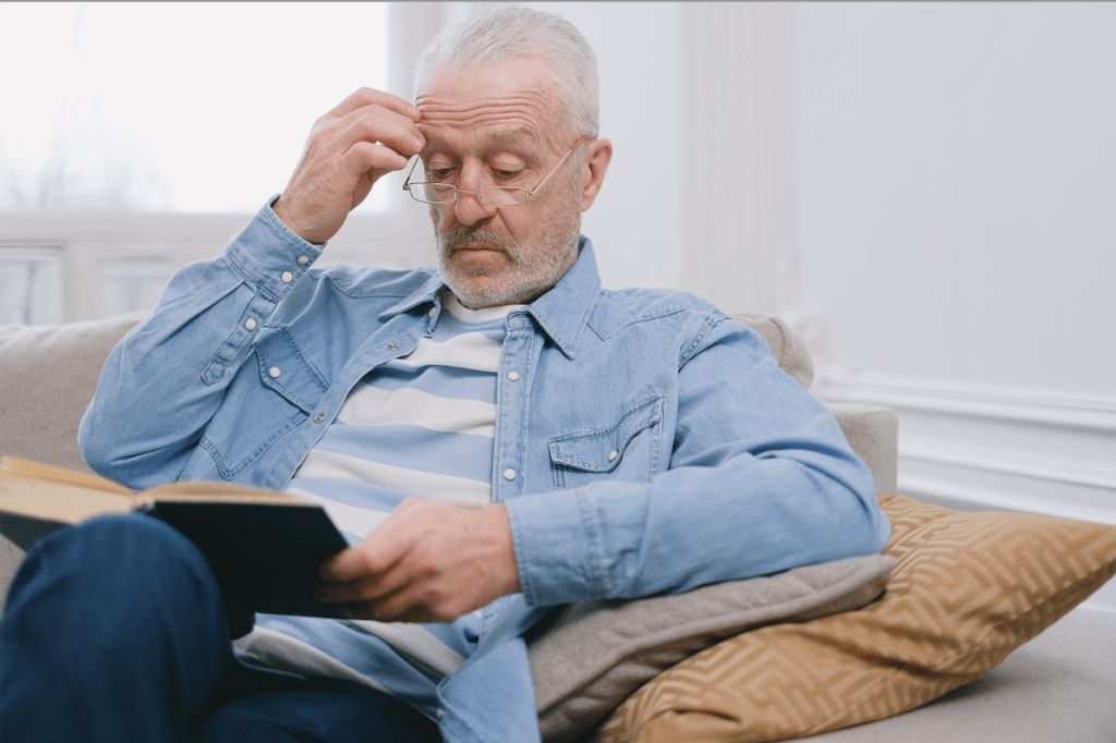 człowiek ze starczowzrocznością czytający książkę